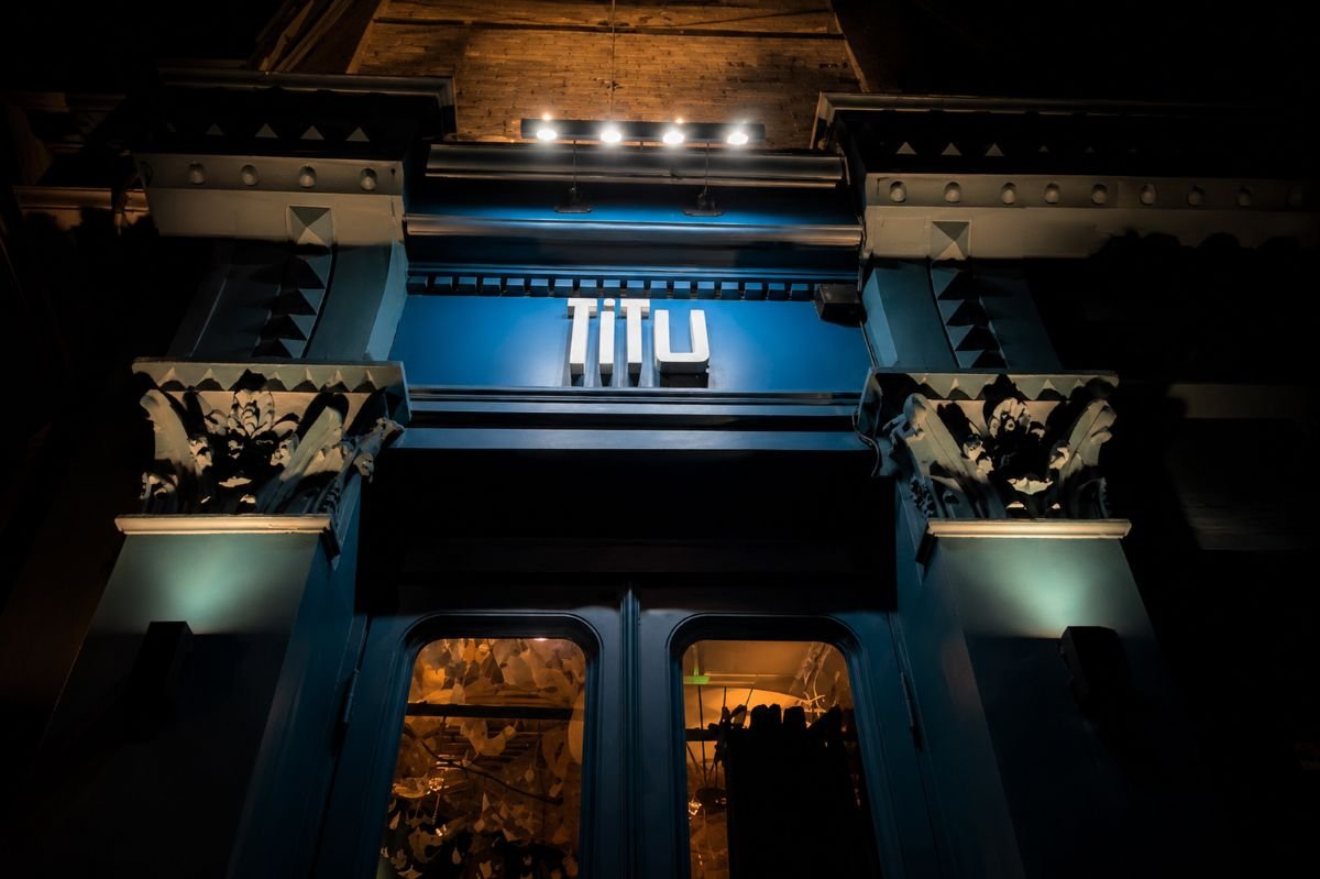 The blue shopfront of Titu Japanese fusion restaurant lit at night on Shepherd Street, Mayfair